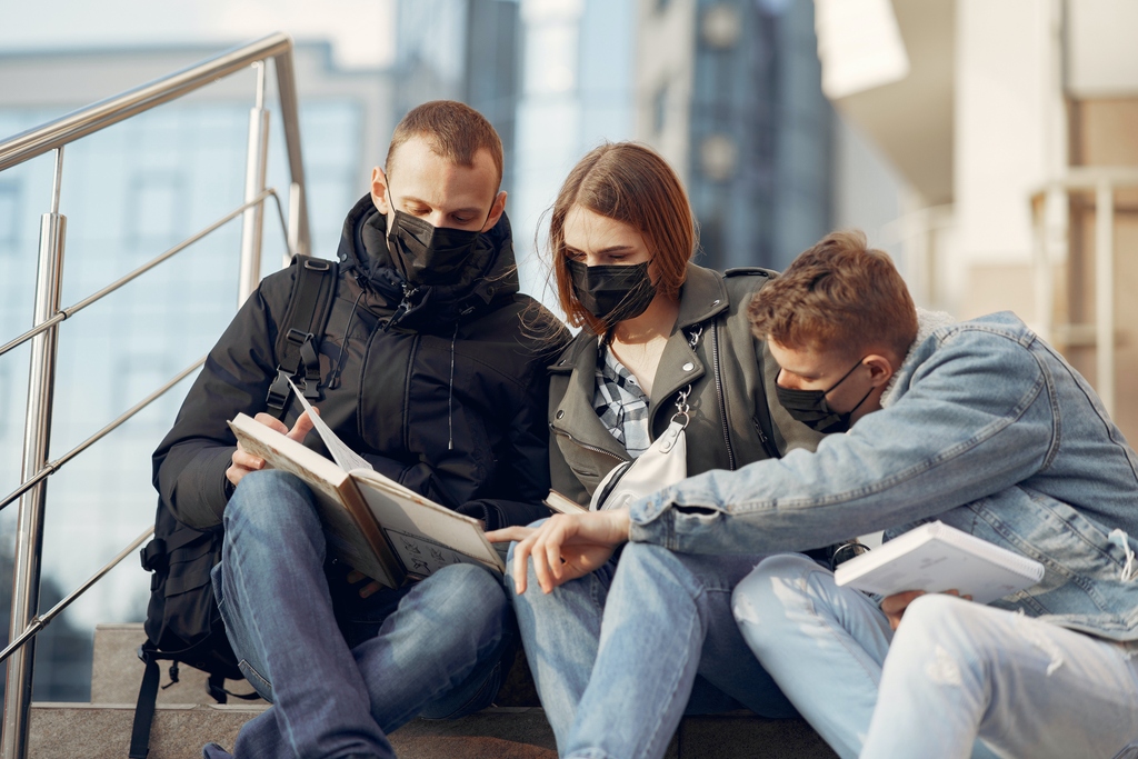 Studenten diskutierend mit einem Buch auf der Treppe